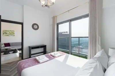 a white bedroom with a bed and a large window at Elegant 2BR - Top Amenities - Elite Business Bay in Dubai