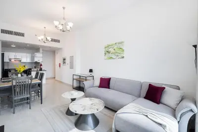 a living room and kitchen with a couch and tables at Elegant 2BR - Top Amenities - Elite Business Bay in Dubai
