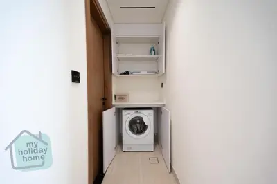 a small laundry room with a washer and dryer at Modern 1BR Apt - Parking - Gym - Play Area in Dubai