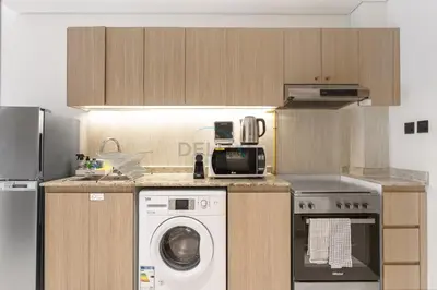 a kitchen with a washing machine and a microwave at Studio with Seamless Mall Access, Steps from the Bus Stop, Binghatti Stars, Dubai Silicon Oasis by Deluxe Holiday Homes in Dubai