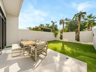 a patio with a table and chairs and a lawn at LUX 4BD Villa, PS5, Minutes from Golf & Downtown in Dubai