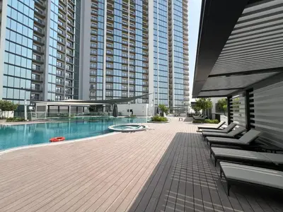a large building with a pool and some lounge chairs at Deluxe 1BR with maid's room, 10 min to Downtown in Dubai