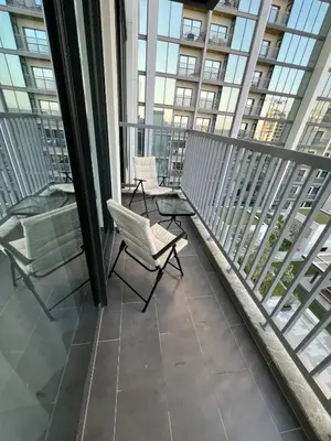 a balcony with two chairs and glass windows at Deluxe 1BR with maid's room, 10 min to Downtown in Dubai