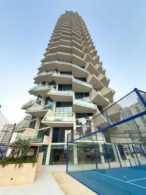 a tall building with a tennis court in front of it at Private Pool - Amazing 1BR Apartment in JVC in Dubai