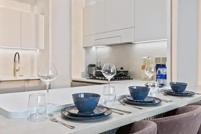 a kitchen with a table with plates and wine glasses at Private Pool - Amazing 1BR Apartment in JVC in Dubai