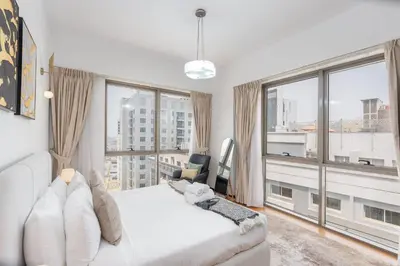 a bedroom with a white bed and large windows at StayShort - Roomy 2BR in Al Barsha with Balcony - Sleeps 4 in Dubai
