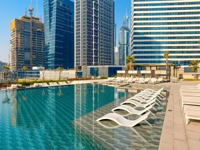 a swimming pool with white lounge chairs and buildings at PENINSULA ONE 1BR by Design Studio in Dubai