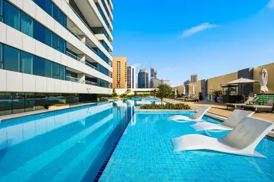 a swimming pool with white chairs next to a building at 3 Bedroom unit at DAMAC maison Canal Views in Dubai