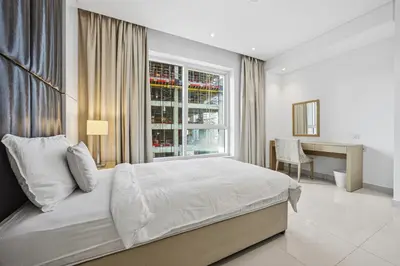 a bedroom with a bed and a desk and a window at 3 Bedroom unit at DAMAC maison Canal Views in Dubai