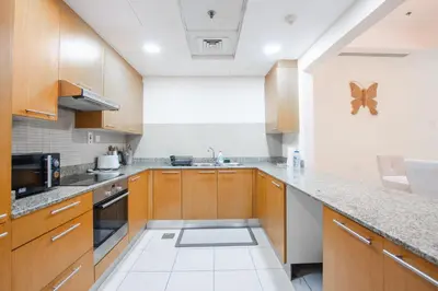 a kitchen with wooden cabinets and granite counter tops at Nivis find- Bay square -1 BHK in Dubai