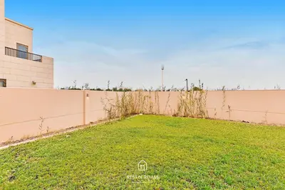 a large grassy yard next to a fence at Luxury Elie Saab 3BR Villa in Jasmine Lane in Dubai