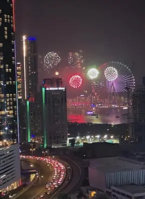 a city at night with fireworks and a ferris wheel at Elite Residence, Marina in Dubai