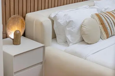 a white bed with white pillows and a night stand at Modern Downtown Apartment plus Pool plus Khalifa View in Dubai