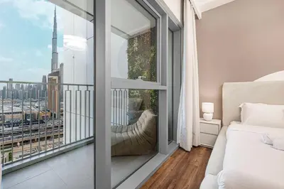 a bedroom with a balcony with a view of the city at Modern Downtown Apartment plus Pool plus Khalifa View in Dubai