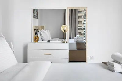a white bedroom with a bed and a mirror at Modern 1BR in Dubai Marina with Balcony Gym & Pool in Dubai