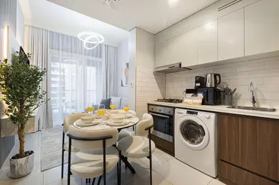 a kitchen with a table and a washing machine at Stunning Canal View 1BR Apartment Burj Khalifa And Dubai Mall 10 Min Walk Ideal for Up to 4 Guests in Dubai