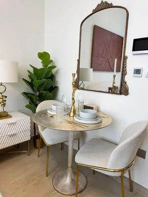 a table with chairs and a mirror in a room at Posh and Bright New Studio Apartment in Dubai