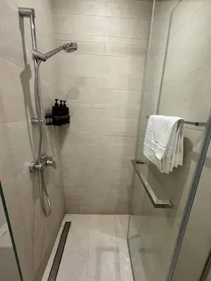a bathroom with a shower with a glass door at Posh and Bright New Studio Apartment in Dubai