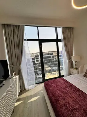 a bedroom with a bed and a large window at Posh and Bright New Studio Apartment in Dubai