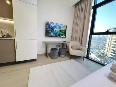 a white room with a tv and a table and a chair at Urban SkyView Apartment Near Downtown Dubai in Dubai