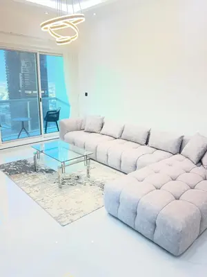 a living room with a large couch and a glass table at Stunning Modern 1BR Apartment Lake View JLT Lake Terrace in Dubai