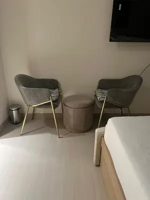 two chairs in a room with a bed and a tv at 15 min from Dubai Marina & JBR beach Studio apartment AZURE BINGHATTI JVC in Dubai