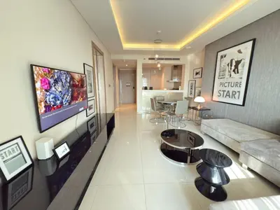 a living room with a couch and a tv on a wall at AMAKIN Damac Paramount in Dubai