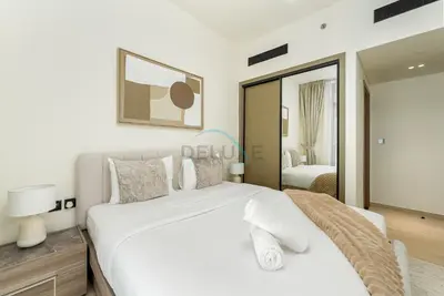 a bedroom with a large white bed and a mirror at Located Near Community Parks, Convenient Stores, an RTA Bus Stop, And Just Minutes From The Mall - Binghatti Emerald, JVC by Deluxe Holiday Homes in Dubai