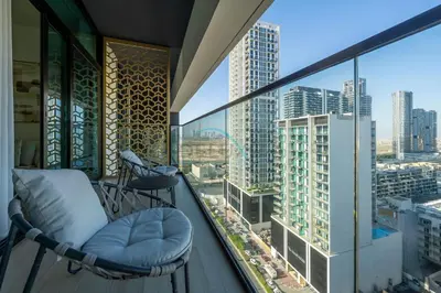 a balcony with chairs and a view of a city at Located Near Community Parks, Convenient Stores, an RTA Bus Stop, And Just Minutes From The Mall - Binghatti Emerald, JVC by Deluxe Holiday Homes in Dubai