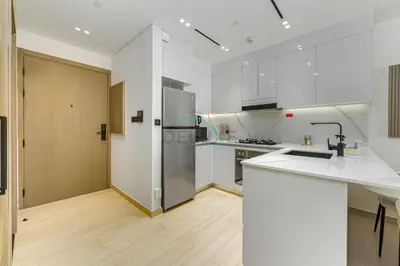 a kitchen with white cabinets and a stainless steel refrigerator at Located Near Community Parks, Convenient Stores, an RTA Bus Stop, And Just Minutes From The Mall - Binghatti Emerald, JVC by Deluxe Holiday Homes in Dubai