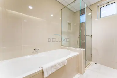a bathroom with a tub and a glass shower at 4BR plus Maids Room Villa Near Nad Al Sheba Mall, With Easy Access to Major Dubai Attractions - Nad Al Shiba Third, Nad Al Sheba by Deluxe Holiday Homes in Dubai