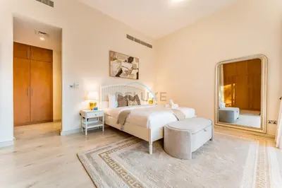 a white bedroom with a bed and a table at 4BR plus Maids Room Villa Near Nad Al Sheba Mall, With Easy Access to Major Dubai Attractions - Nad Al Shiba Third, Nad Al Sheba by Deluxe Holiday Homes in Dubai