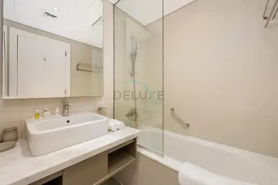 a bathroom with a sink and a tub and a mirror at Dubai Water Canal View, Minutes away from Burj Khalifa and Dubai Mall, Near Metro Bus Station - Prive by Damac B, Business Bay by Deluxe Holiday Homes in Dubai