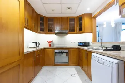 a kitchen with wooden cabinets and white appliances at Modern Retreat in The Views with Balcony & Pool in Dubai