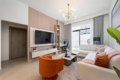 a living room with a white couch and a tv at Few Minutes Walk to Circle Mall, Conveniently Close Community Park, and Near the Bus Station for Effortless Metro Access - Oxford Terraces, JVC by Deluxe Holiday Homes in Dubai