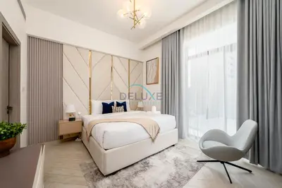 a bedroom with a white bed and a white chair at Few Minutes Walk to Circle Mall, Conveniently Close Community Park, and Near the Bus Station for Effortless Metro Access - Oxford Terraces, JVC by Deluxe Holiday Homes in Dubai