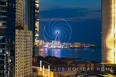 a large ferris wheel in a city at night at LUX The Sky Dubai Eye View Suite in Dubai