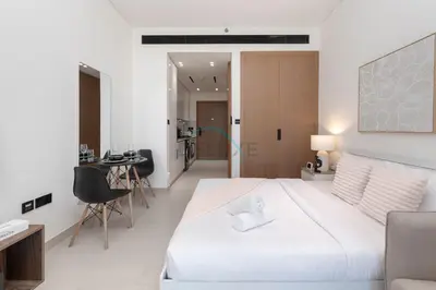 a bedroom with a large white bed and a table at High-Floor Studio Overlooking the Community, Just a Short Drive to Miracle Garden, Binghatti Azure, JVC by Deluxe Holiday Homes in Dubai