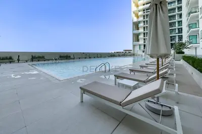 a row of lounge chairs next to a swimming pool at High-Floor Studio Overlooking the Community, Just a Short Drive to Miracle Garden, Binghatti Azure, JVC by Deluxe Holiday Homes in Dubai