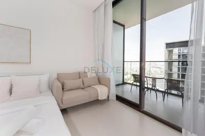 a white living room with a couch and a balcony at High-Floor Studio Overlooking the Community, Just a Short Drive to Miracle Garden, Binghatti Azure, JVC by Deluxe Holiday Homes in Dubai