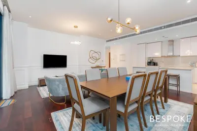 a dining room and kitchen with a wooden table and chairs at Bespoke Holiday Homes - 2BR plus Kids room in City Walk with Direct Pool Access in Dubai