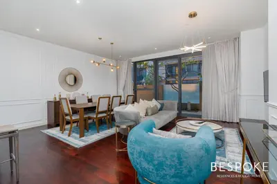 a living room with a blue couch and a table at Bespoke Holiday Homes - 2BR plus Kids room in City Walk with Direct Pool Access in Dubai