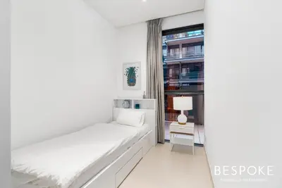 a white bedroom with a bed and a window at Bespoke Holiday Homes - 2BR plus Kids room in City Walk with Direct Pool Access in Dubai