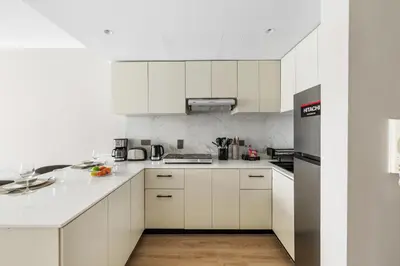 a white kitchen with white cabinets and appliances at Modern 1BR by the Lake Near DMCC Metro Station in Dubai