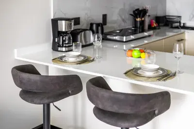a kitchen counter with two chairs and a table with glasses at Modern 1BR by the Lake Near DMCC Metro Station in Dubai
