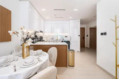 a kitchen with white walls and white tables and chairs at Close to Community Park, Minutes Walk from Circle Mall, and Short Drive to Dubai Miracle Garden and Butterfly Garden - Binghatti Amber, JVC by Deluxe Holiday Homes in Dubai