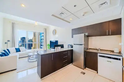 a kitchen with a refrigerator and a couch in a room at Spacious 1BHK Apt with Canal View in Dubai Marina in Dubai