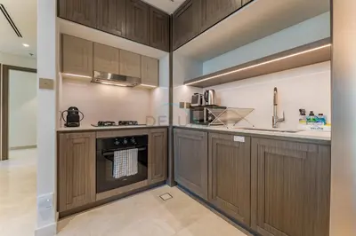 a kitchen with wooden cabinets and an oven at Direct Private Beach Access, Proximity To Key Dubai Attractions Like Dubai Marina, Palm Jumeirah, And JBR Walk - Palace Beach Residence Tower 2, Emmar Beachfront by Deluxe Holiday Homes in Dubai