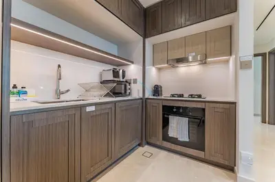 a kitchen with wooden cabinets and a sink at Prestigious Waterfront Community, Beachfront Living Near Dubai Marina and Top Dining Hotspots - Palace Beach Residence Tower 2, Emaar Beachfront by Deluxe Holiday Homes in Dubai