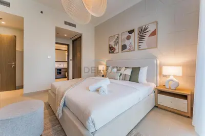 a bedroom with a large white bed and a table at Prestigious Waterfront Community, Beachfront Living Near Dubai Marina and Top Dining Hotspots - Palace Beach Residence Tower 2, Emaar Beachfront by Deluxe Holiday Homes in Dubai